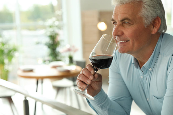 Senior man with glass of wine in restaurant. Space for text - Foto, imagen