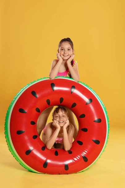 niedlichen kleinen Mädchen mit hellen aufblasbaren Ring auf gelbem Hintergrund - Foto, Bild