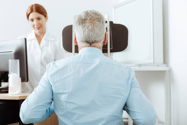 Grey-haired retired man having eye sight analysis at private clinic - Foto, Imagen