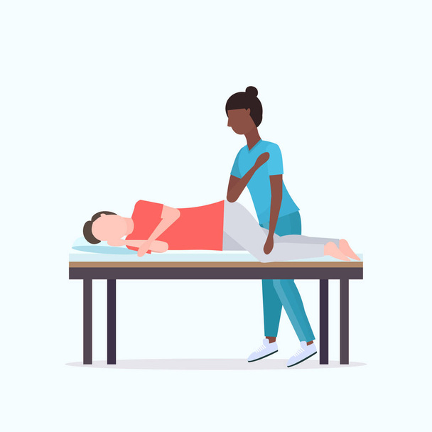 guy lying on massage bed african american masseuse therapist doing healing treatment massaging injured patient manual sport physical therapy rehabilitation concept full length - Vector, Image