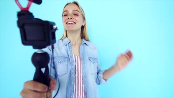美しい女の子のブロガーは、カメラ孤立青い背景で自分自身を緩和します - 映像、動画