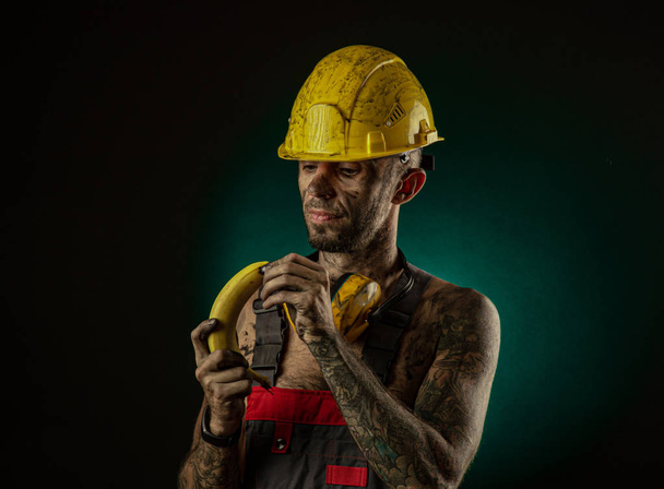 Portrait of a happy smiling miner eating a banana for lunch - Fotoğraf, Görsel