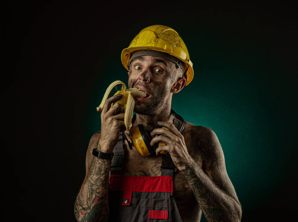 Egy boldog mosolygós bányász portréja ebédre egy banánt - Fotó, kép