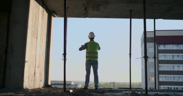 Ingegnere Costruttore sul tetto dell'edificio al tramonto si trova in VR occhiali e muove le mani utilizzando l'interfaccia del futuro. Ingegnere futuristico del futuro. La vista dal retro
. - Filmati, video