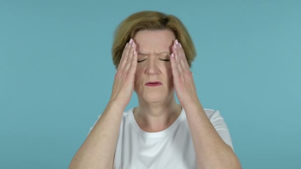 Öregasszony a fejfájás izolált kék háttér - Felvétel, videó