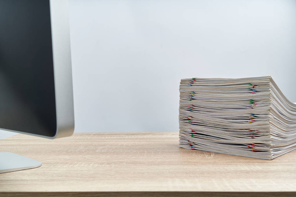 Pilha de relatório de sobrecarga de papelada e computador na mesa de madeira
 - Foto, Imagem