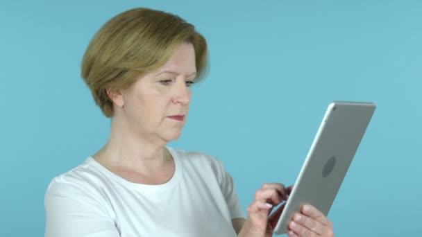 Old Woman Excited for Success while Using Tablet Isolated on Blue Background - Footage, Video