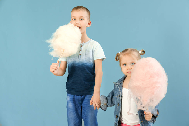 Cute little children with cotton candy on color background - Photo, Image