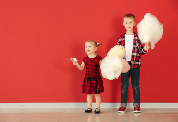 Cute little children with cotton candy against color wall - Photo, Image