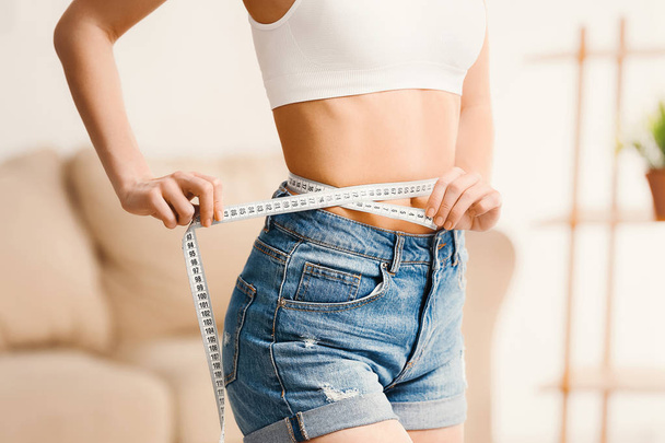 Woman with measuring tape at home. Weight loss concept - Foto, Bild