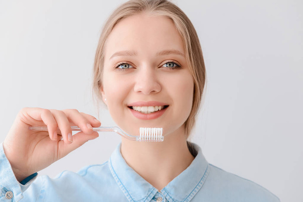 Woman with toothbrush on light background. Concept of dental hygiene - Фото, изображение