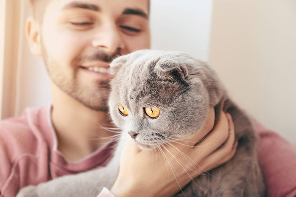 Young man with cute funny cat at home - Photo, Image