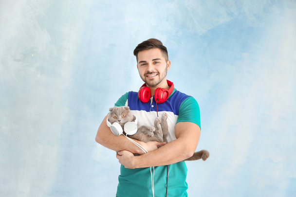 Genç adam ve renkli arka planda kulaklıklar ile onun sevimli komik kedi - Fotoğraf, Görsel
