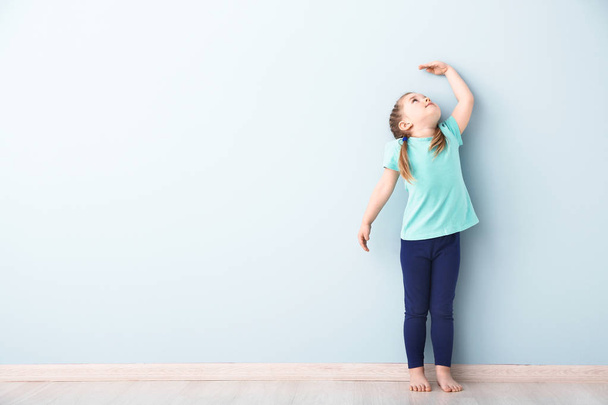 Маленька дівчинка вимірює висоту біля стіни
 - Фото, зображення