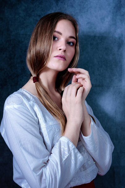 Dramatic portrait of a beautiful lonely girl with blond hair isolated on gray background - Fotó, kép