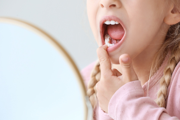 Klein meisje controleren witheid van haar tanden thuis, close-up - Foto, afbeelding