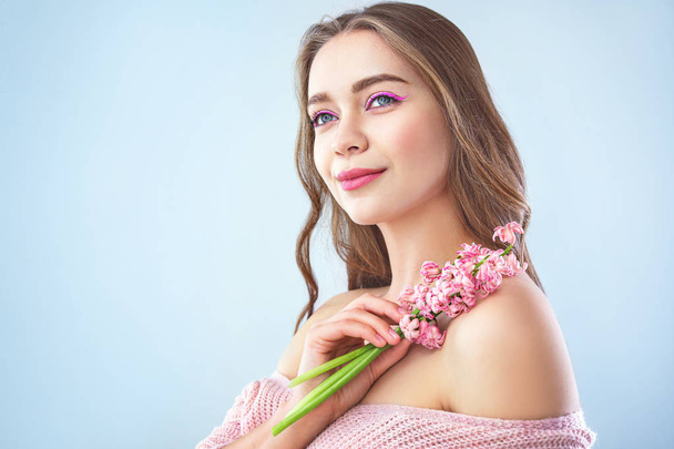 Beautiful young woman with hyacinth flowers on light background - Foto, imagen