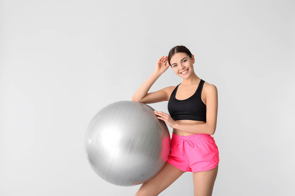 Giovane donna sportiva con fitball su sfondo grigio
 - Foto, immagini