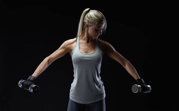 Fitness woman in training pumping up muscles with dumbbell - Fotoğraf, Görsel