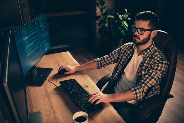 Close up photo not smiling handsome he him his guy coder typing php css keyboard development outsource IT processing language two monitors table office agency wear specs formalwear plaid shirt - Foto, immagini
