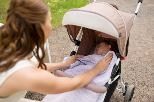 mother with child in stroller at summer park - Photo, Image