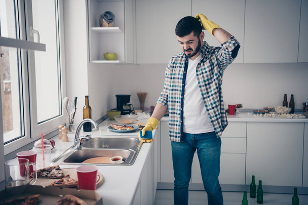 Portrait of his he nice attractive minded annoyed bearded guy wearing checked shirt mess chaos around maid service in modern light white interior style kitchen indoors - Foto, imagen