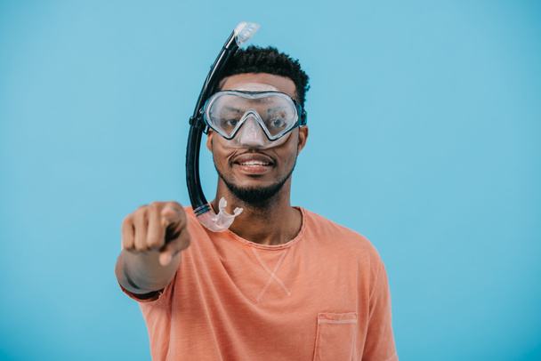 selective focus of african american man in diving mask pointing with finger isolated on blue  - Foto, immagini