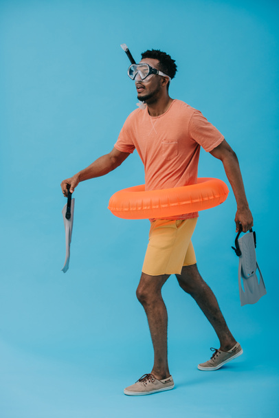 African American Man w maska do nurkowania trzyma płetwy i chodzenie na niebiesko  - Zdjęcie, obraz
