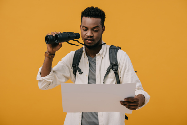 curly african american man holding binoculars and looking at blank paper isolated on orange - Φωτογραφία, εικόνα