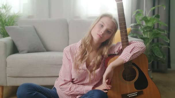 A young man photographs a girl with a guitar at her home - Video