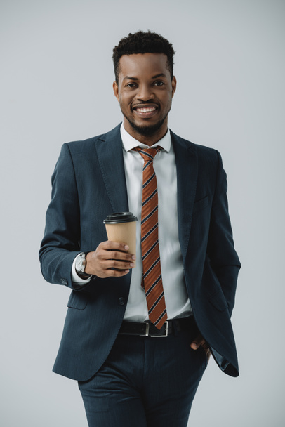 cheerful african american businessman holding paper cup isolated on grey  - Photo, Image
