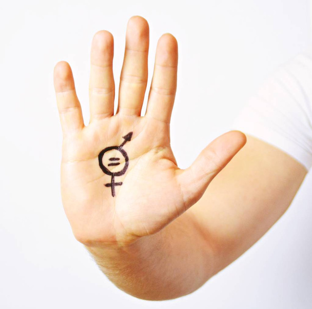 Parikymppinen mies on maalannut käteensä merkin sukupuolten tasa-arvosta ja näyttää sen kameralle - käsitteen miesten ja naisten tasa-arvon vaatimisesta
  - Valokuva, kuva