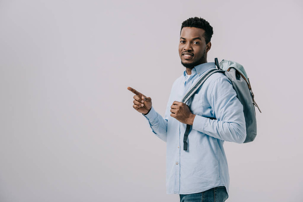 cheerful african american man with backpack pointing with finger isolated on grey  - Foto, afbeelding