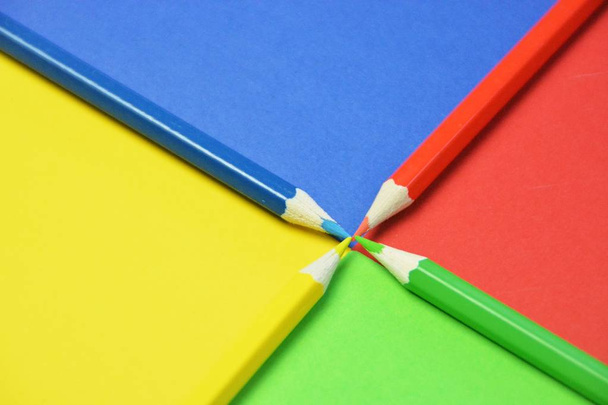 Cuatro crayones de diferentes colores dividen un área en cuatro niveles, que a su vez tienen el color del crayón un concepto con superficie dividida y lápices de colores
  - Foto, Imagen