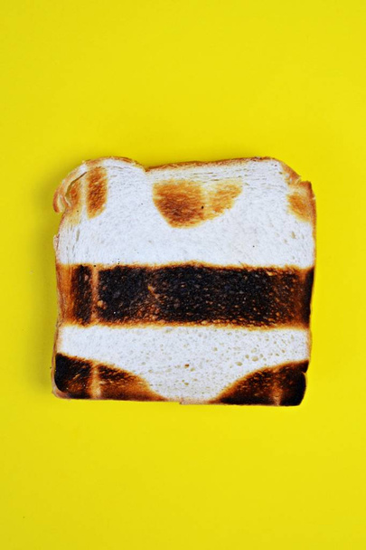 Un toast repose sur une surface colorée. Le pain grillé n'est pas vraiment grillé partout, mais n'a pas de parties grillées sous la forme d'un bikini - Concept abstrait pour les coups de soleil en été
 - Photo, image