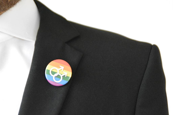 Un homme dans la vingtaine porte un bouton avec le symbole pour transgenre sur sa veste de costume - Concept pour l'acceptation et la tolérance dans la vie professionnelle
 - Photo, image