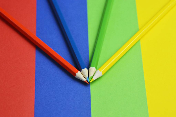 Vier verschillende gekleurde kleurpotloden verdelen een gebied in vier niveaus, die zelf de kleur van het krijt hebben-een concept met gespleten oppervlak en gekleurde pennen  - Foto, afbeelding