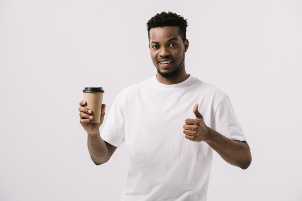 щасливий афроамериканський чоловік тримає паперову чашку і показує великий палець вгору ізольовано на білому
  - Фото, зображення