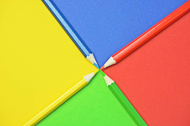 Cuatro crayones de diferentes colores dividen un área en cuatro niveles, que a su vez tienen el color del crayón un concepto con superficie dividida y lápices de colores
  - Foto, imagen