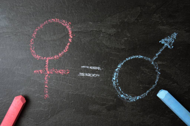 On a dark marble surface, the symbol for man and woman was recorded with different chalks and an actual match between them - concept for the equality of men and women  - Photo, Image