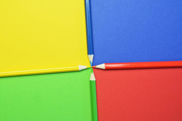 Vier verschillende gekleurde kleurpotloden verdelen een gebied in vier niveaus, die zelf de kleur van het krijt hebben-een concept met gespleten oppervlak en gekleurde pennen  - Foto, afbeelding