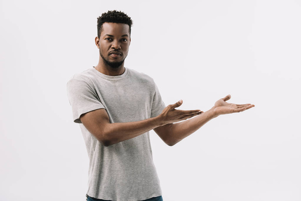 handsome african american man gesturing while looking at camera isolated on white  - 写真・画像
