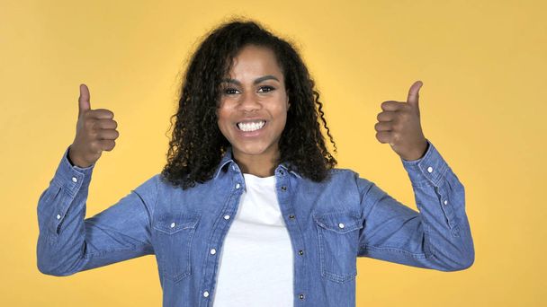 African Girl Gesturing Thumbs Up Isolated on Yellow Background - 写真・画像
