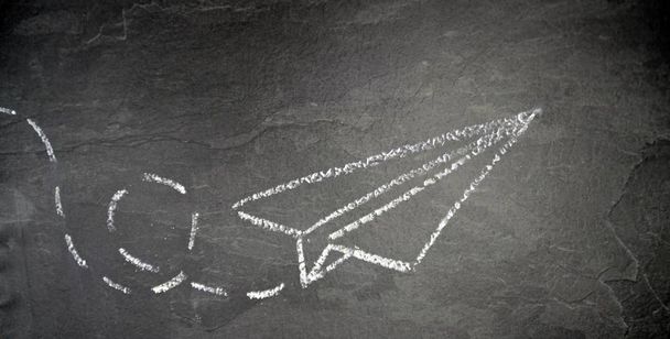 S křídou nakreslené papírové roviny a přerušovanou cestou na tmavém mramorovém pozadí s letadlem létající papírové - Fotografie, Obrázek