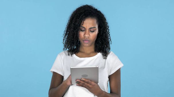 Chica africana navegando por Internet mientras usa la tableta en fondo azul
 - Foto, imagen