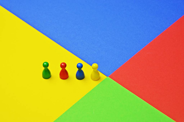 Los hombrecitos de diferentes colores se paran en la misma superficie de color - concepto con figuras de juego, colores y una reunión de éstos para representar la diversidad de un equipo
 - - Foto, Imagen