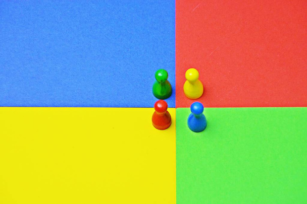 verschiedene farbige Männchen stehen auf derselben farbigen Fläche - Konzept mit Spielfiguren, Farben und einem Treffen dieser, um die Vielfalt einer Mannschaft darzustellen - - Foto, Bild