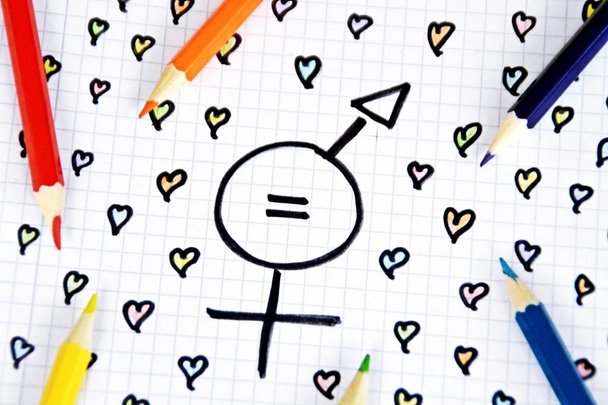 A sign for the equality of man and woman consisting of the respective gender signs and a match with painted hearts and colored pencils on a drawn sheet -equality man and woman symbolically represented - Photo, Image