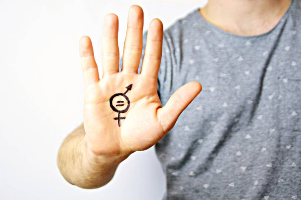 Egy férfi a húszas évek közepén festett jele a nemek közötti egyenlőség a kezét, és megmutatja, hogy a kamera-a koncepció igényes egyenlőség a férfiak és a nők - Fotó, kép