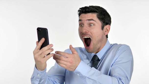 Young Businessman in Shock while Using Smartphone - 写真・画像
